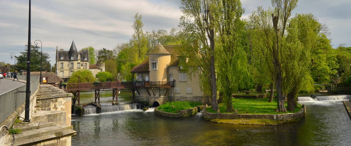 A river with a bridge, a tower, and a castle in the background.