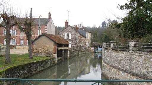 Châtillon-Coligny, Loiret, France. Boulevard de la République, at the corner of the restaurant "Le Coligny". An arm of the Loing river, looking downstream as it's leeaving the moat that runs against what used to be the town defence wall (the moat is immediately upstream from this bridge, behind us).