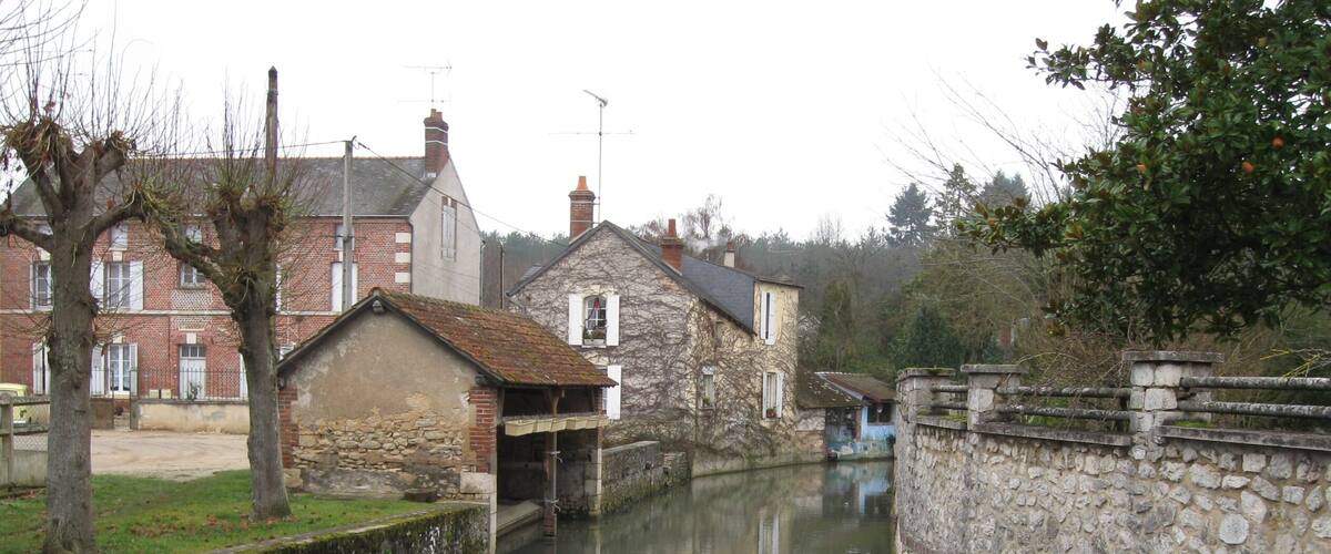 A narrow canal flanked by stone buildings and a metal railing.