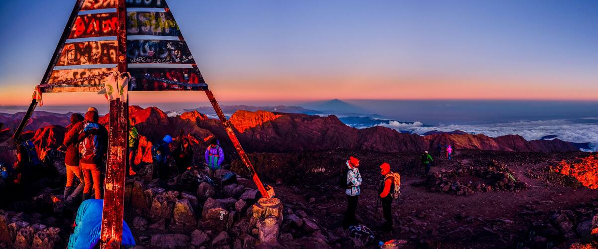 A group of hikers on a rocky mountain with a pyramid structure in the foreground.