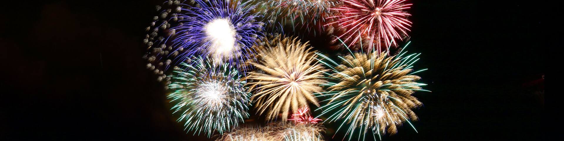 Una colina con fuegos artificiales explotando en el cielo nocturno.