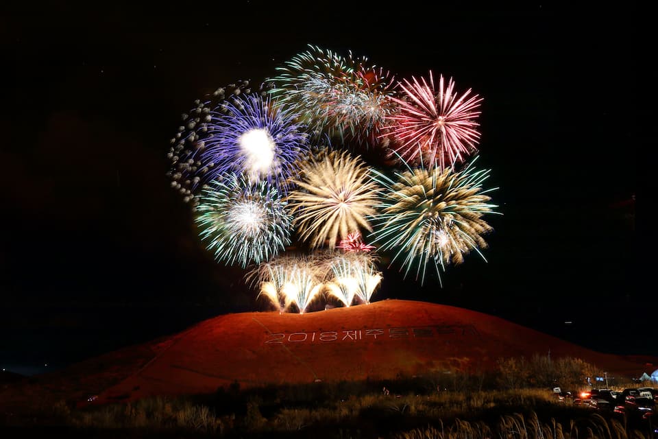 Een heuvel met vuurwerk dat in de nachtelijke hemel ontploft.