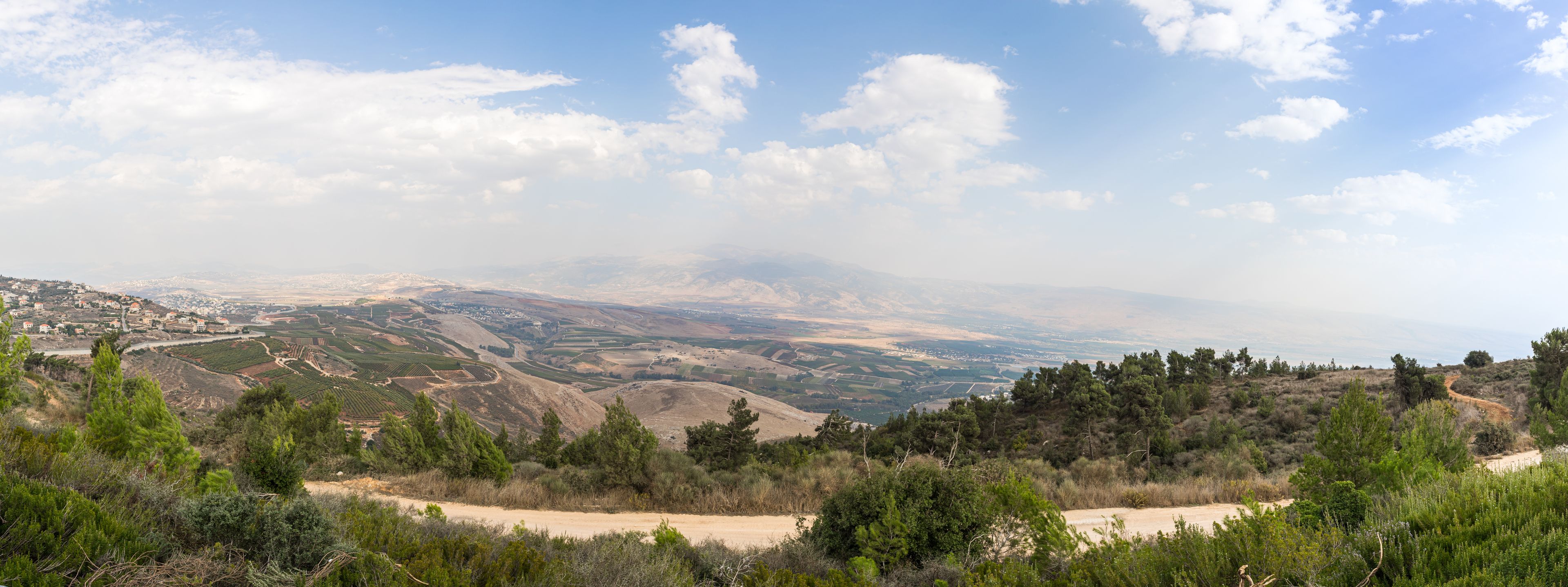 Eine gebirgige Landschaft mit terrassierten Feldern, einer kurvigen Straße und verstreuten Gebäuden.