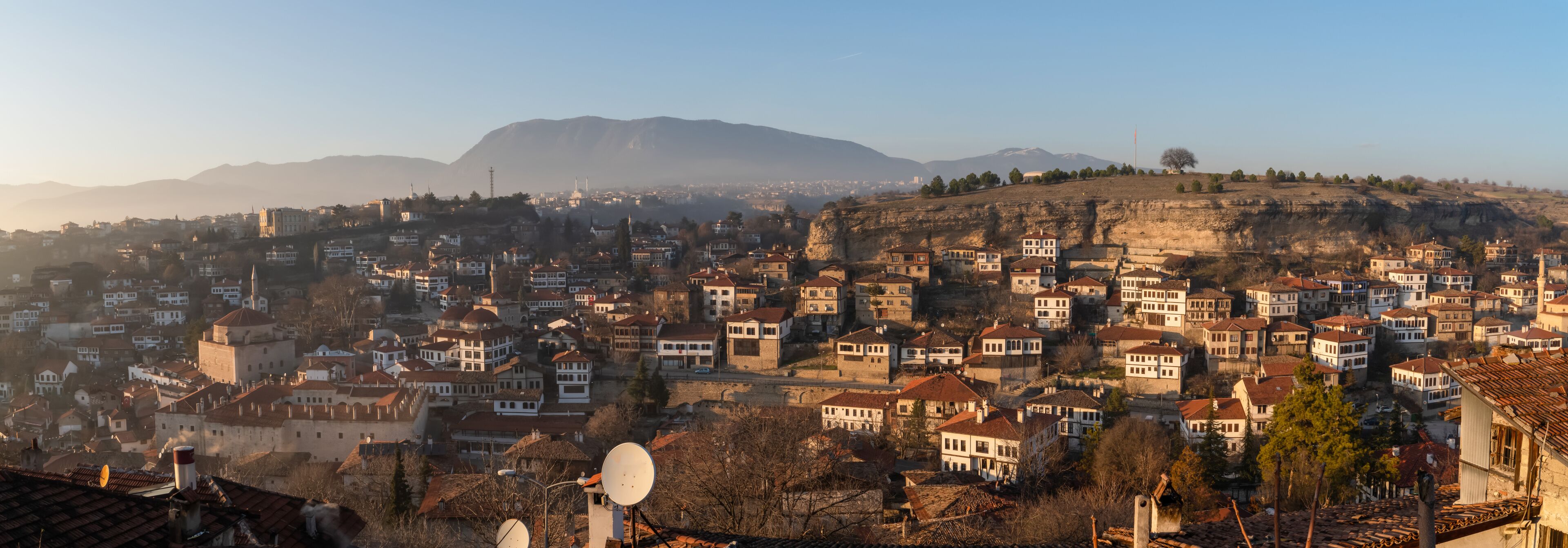 A cityscape with a prominent hill, numerous buildings, and a clear sky.