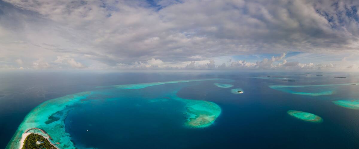 An aerial view of a turquoise coral reef with clear waters and small islands.