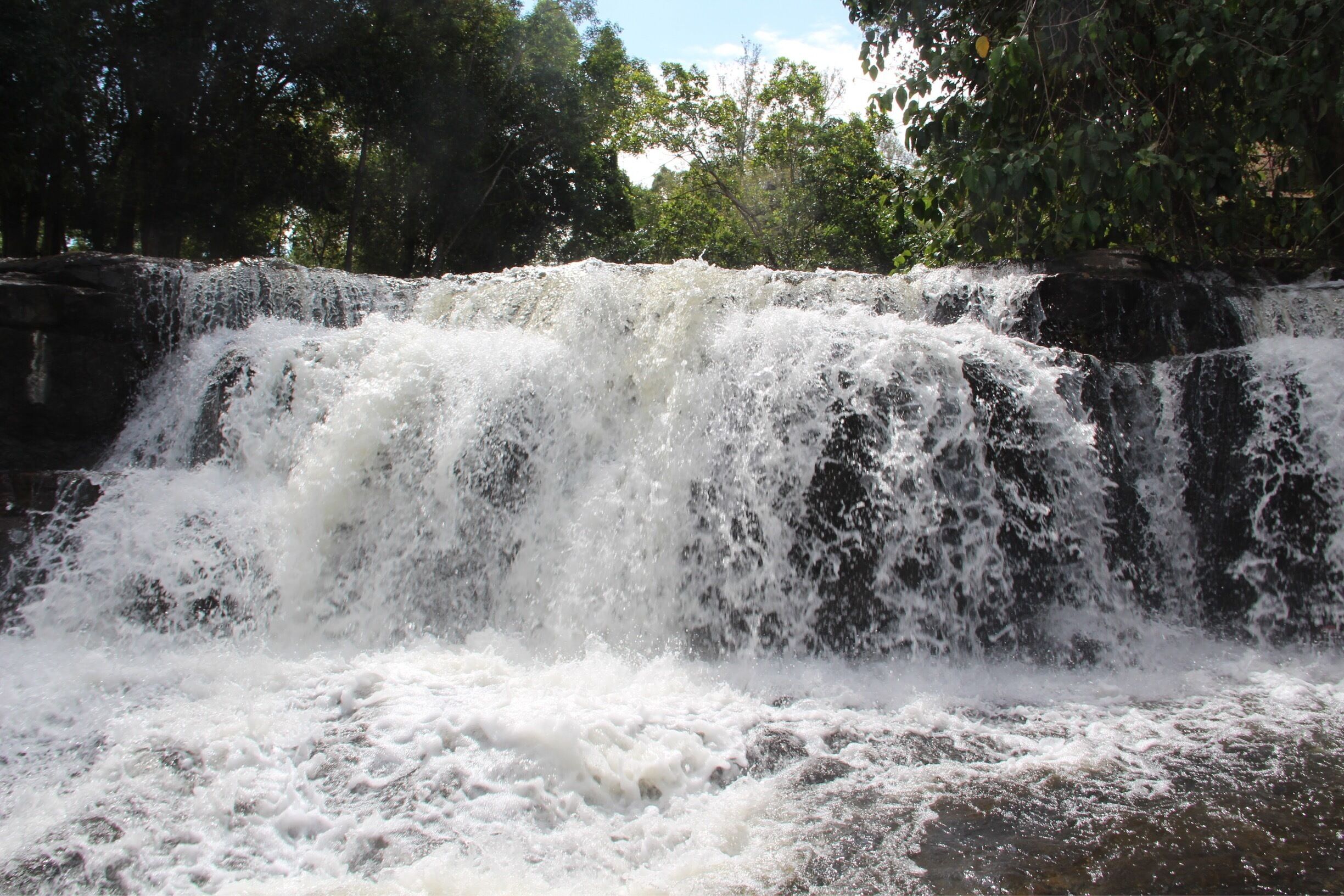 A waterfall cascading over rocks surrounded by trees.