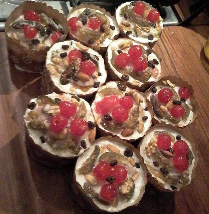 A wooden table with several open-faced sandwiches topped with red cherries, nuts, and seeds.