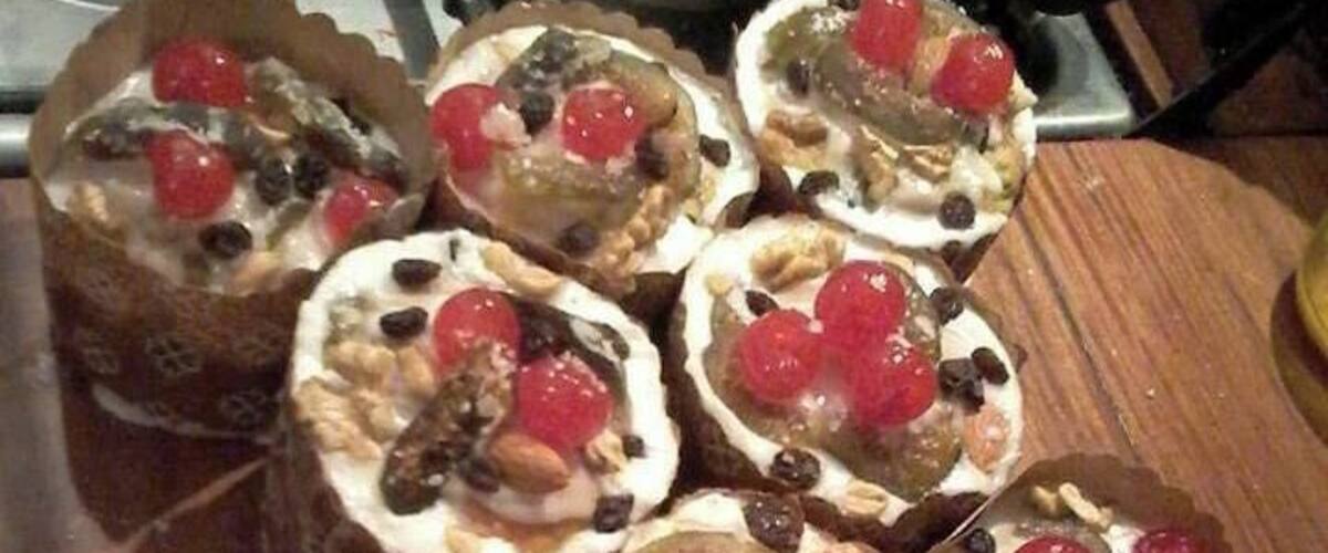 A wooden table with several open-faced sandwiches topped with red cherries, nuts, and seeds.