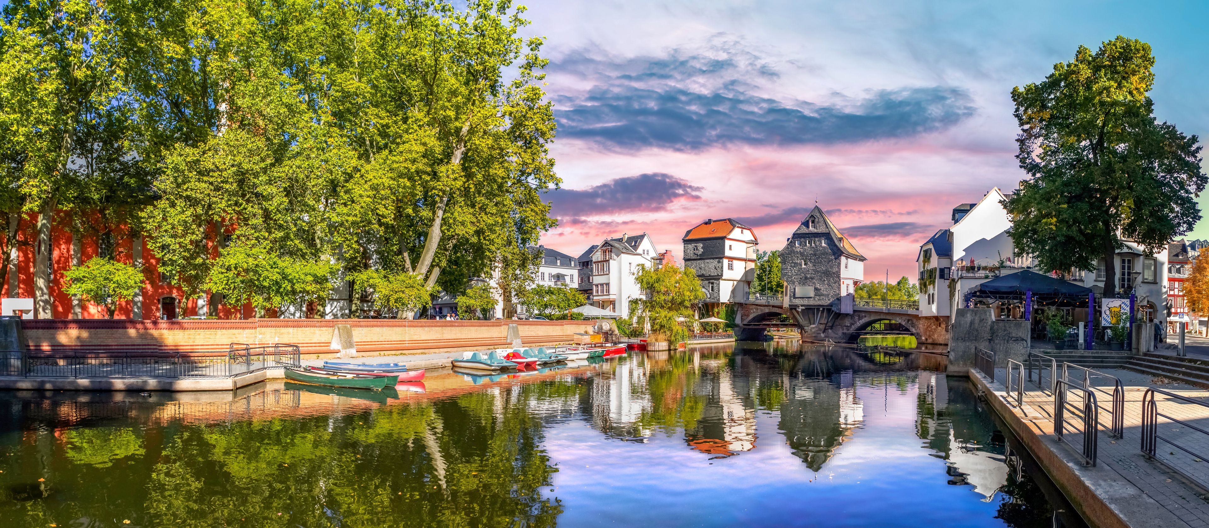 Un canale con barche, un ponte e edifici che si riflettono nell'acqua.