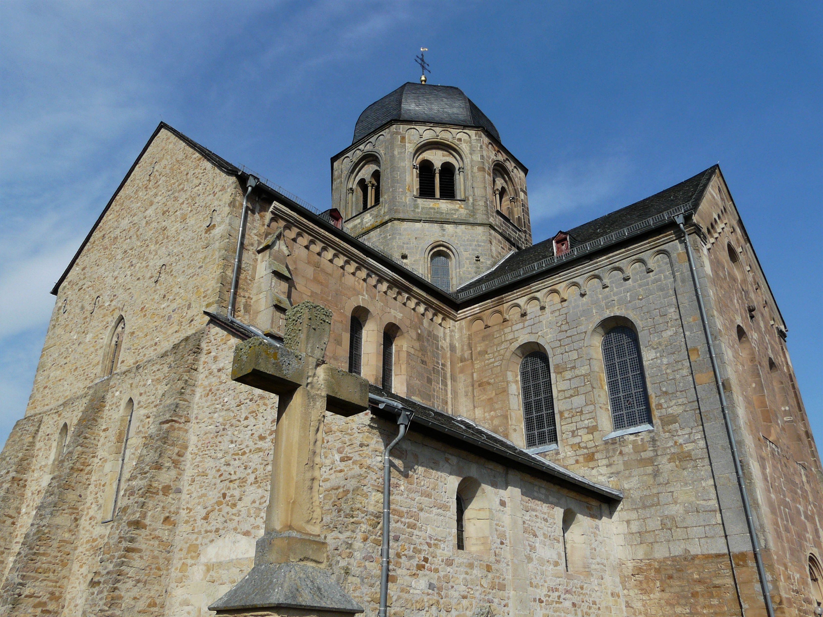Una iglesia histórica de piedra con una torre de campanas y ventanas de arco.