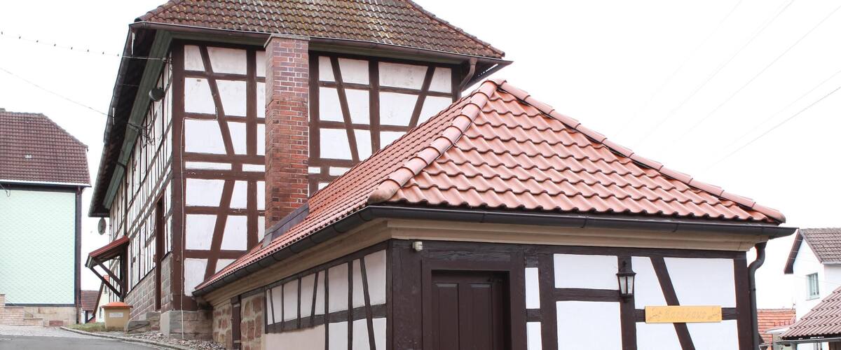 A traditional half-timbered building with a clock tower and a red-tiled roof.