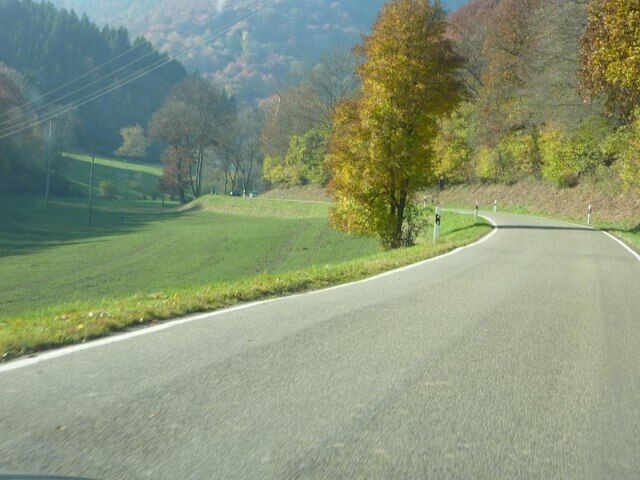 A winding road through a hilly landscape with autumn-colored trees.