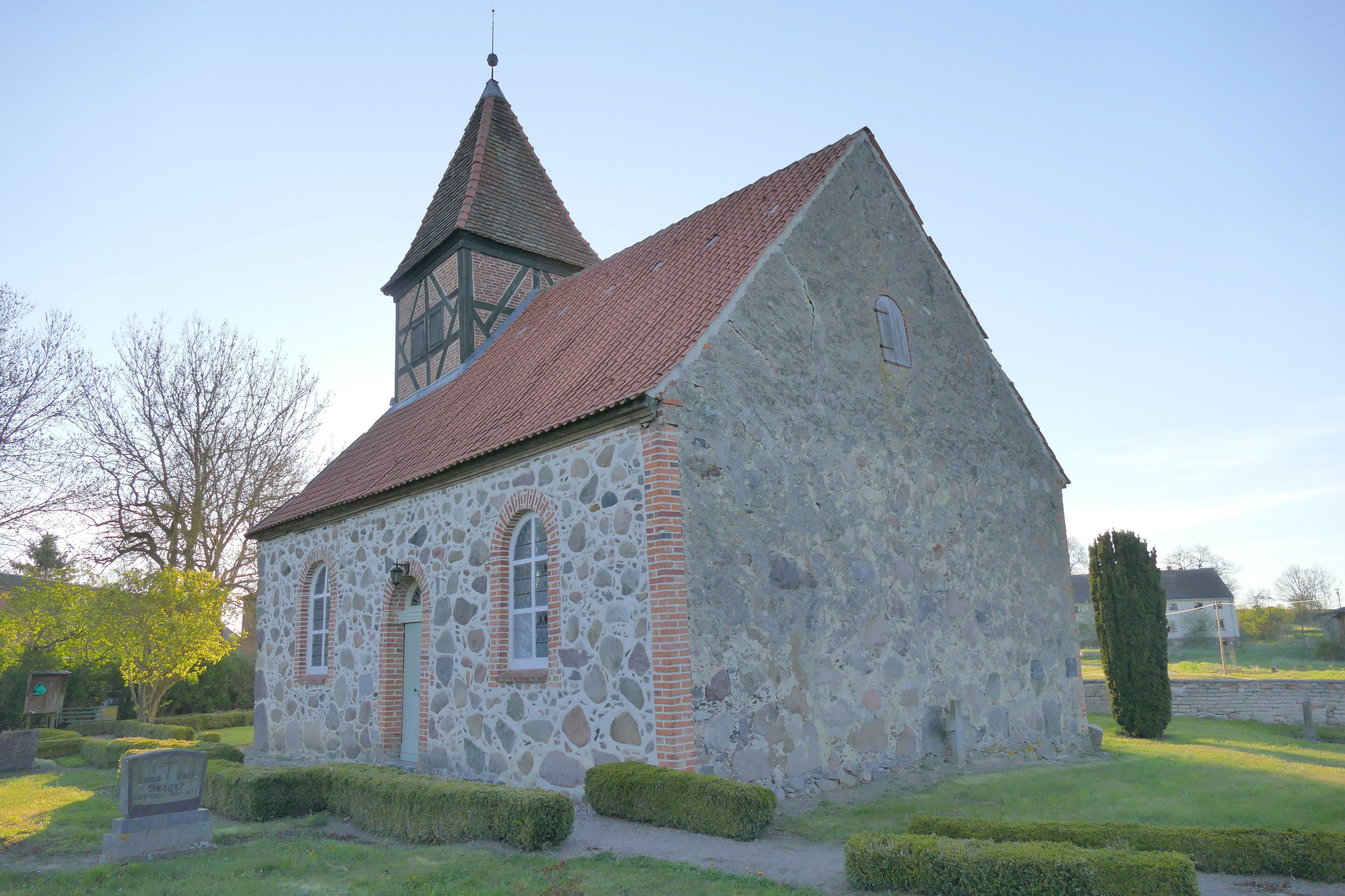 A stone church with a red-tiled roof and a bell tower.
