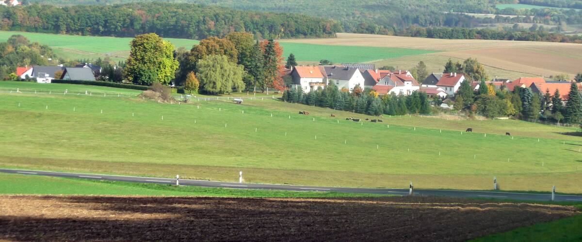 A rural landscape with fields, houses, and a road.