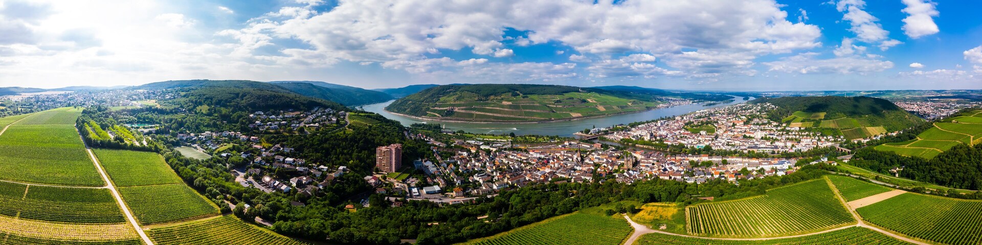 Vista panorâmica de uma cidade situada entre campos verdes exuberantes e um rio.