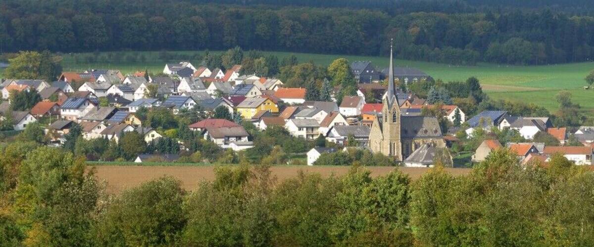 A rural village with houses, a church, and rolling green fields.
