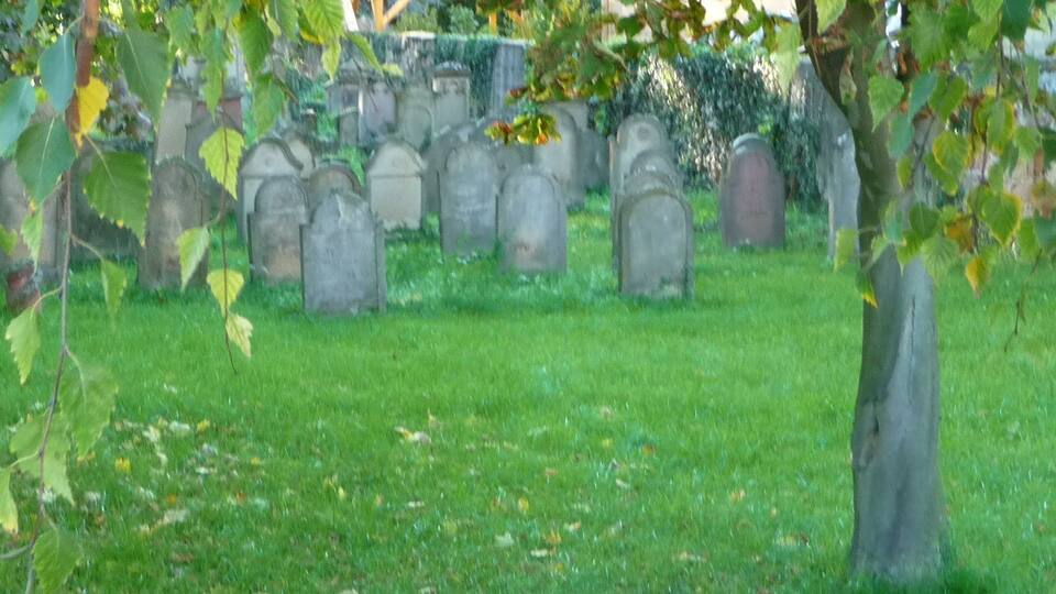 A cemetery with headstones and a wooden structure in the background.