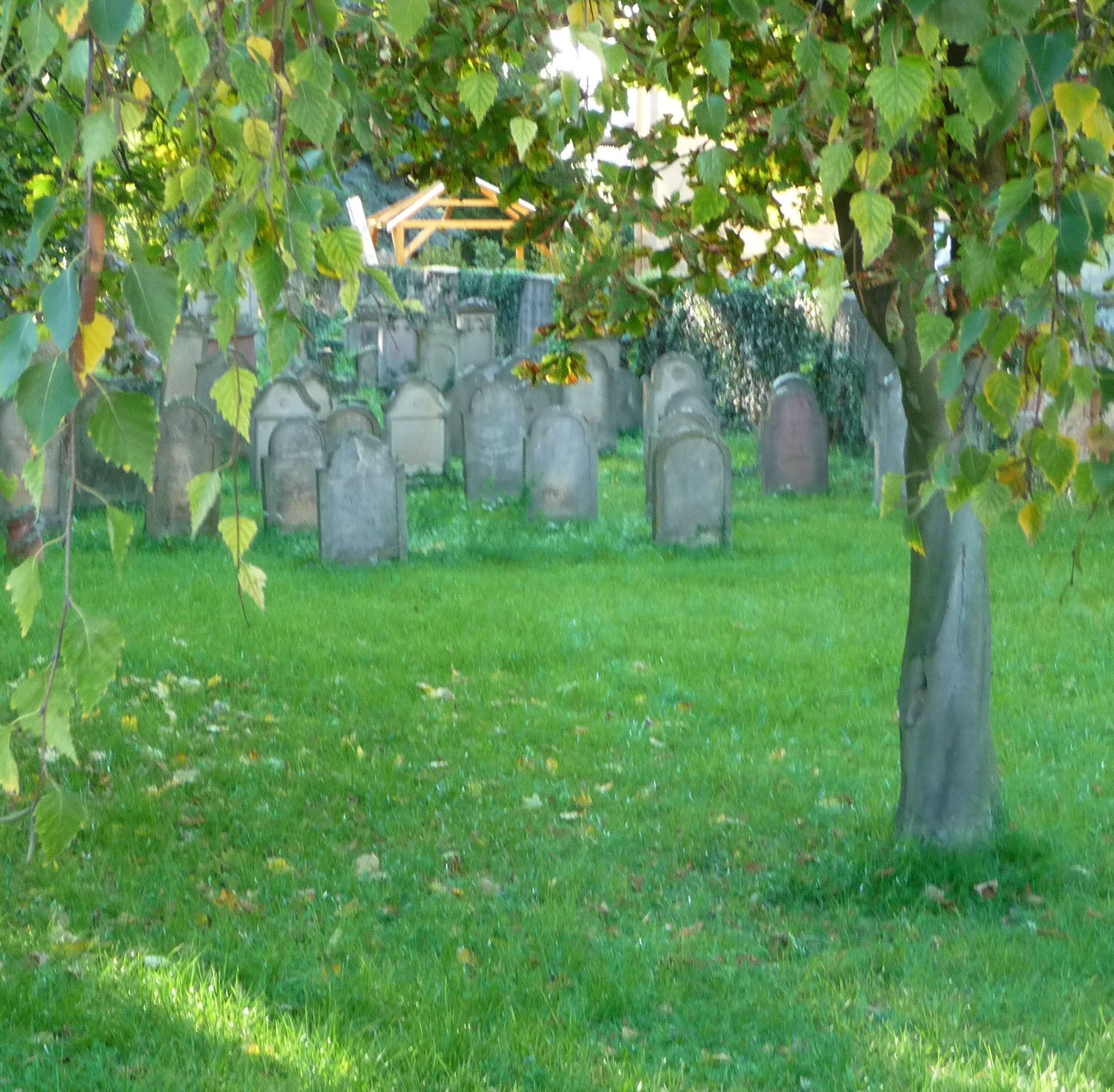 A cemetery with headstones and a wooden structure in the background.