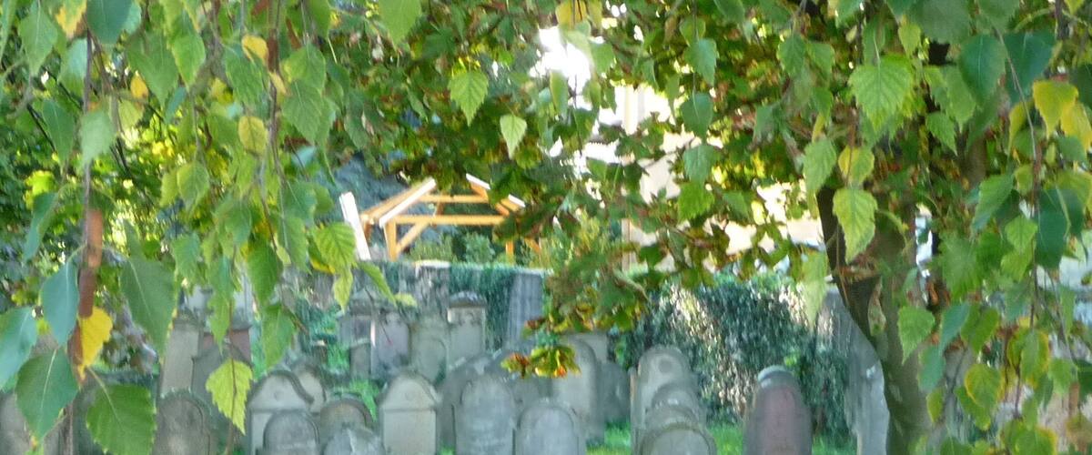 A cemetery with headstones and a wooden structure in the background.