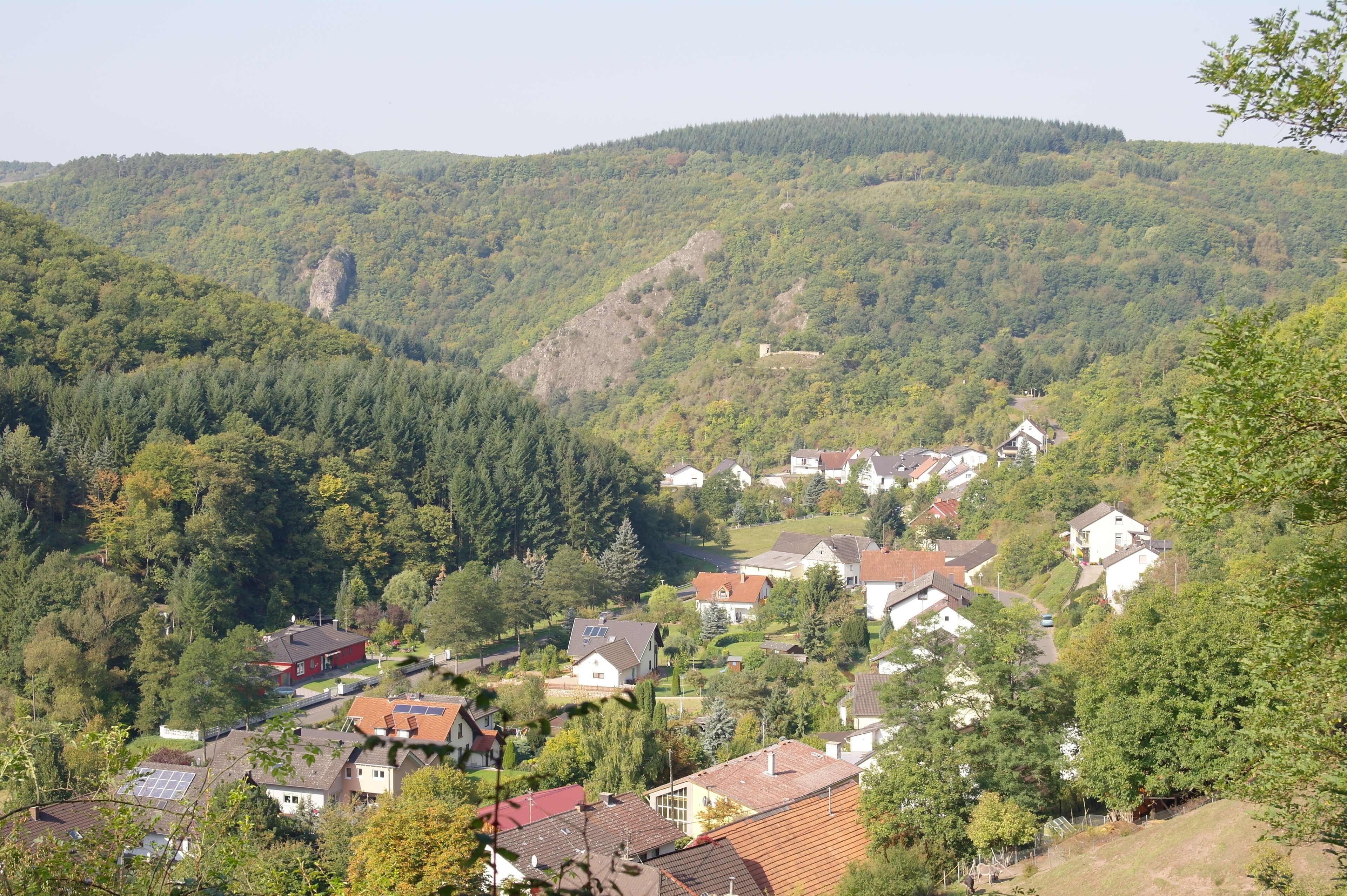 A village nestled in a valley surrounded by forested hills.
