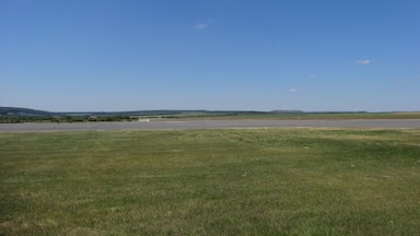 A grassy field with a clear blue sky and distant hills.