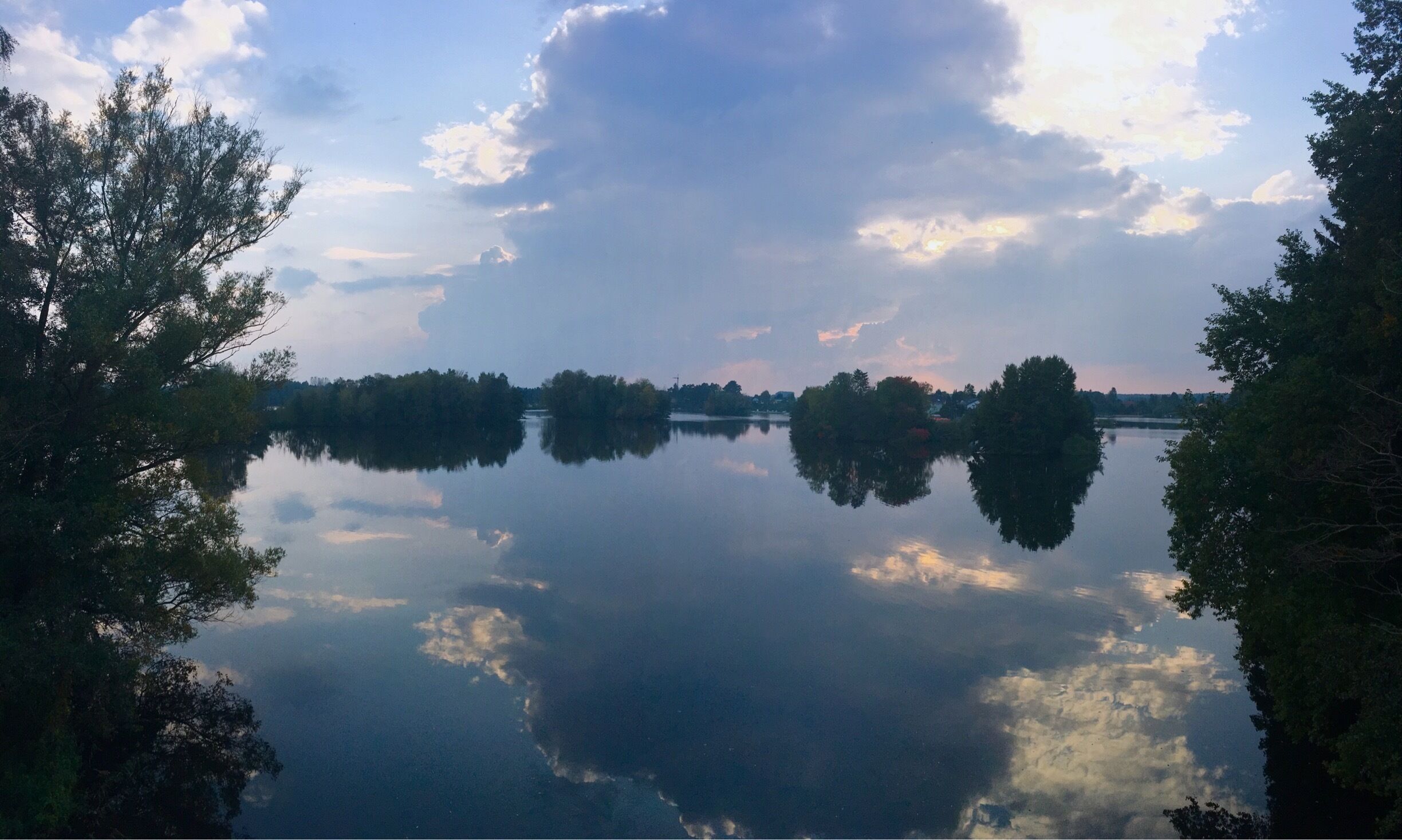 A calm lake with reflections of trees and clouds.