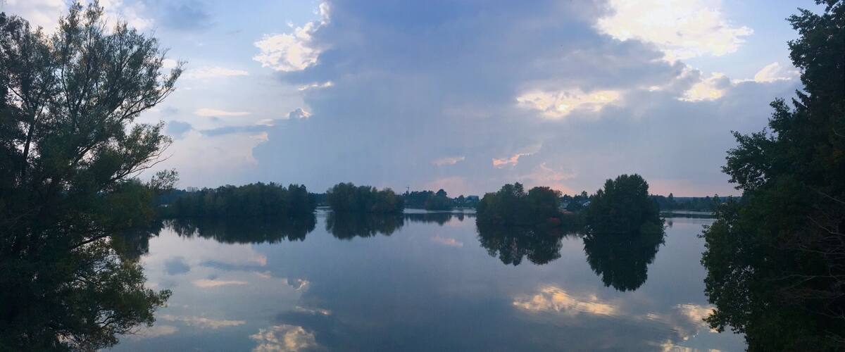 A calm lake with reflections of trees and clouds.