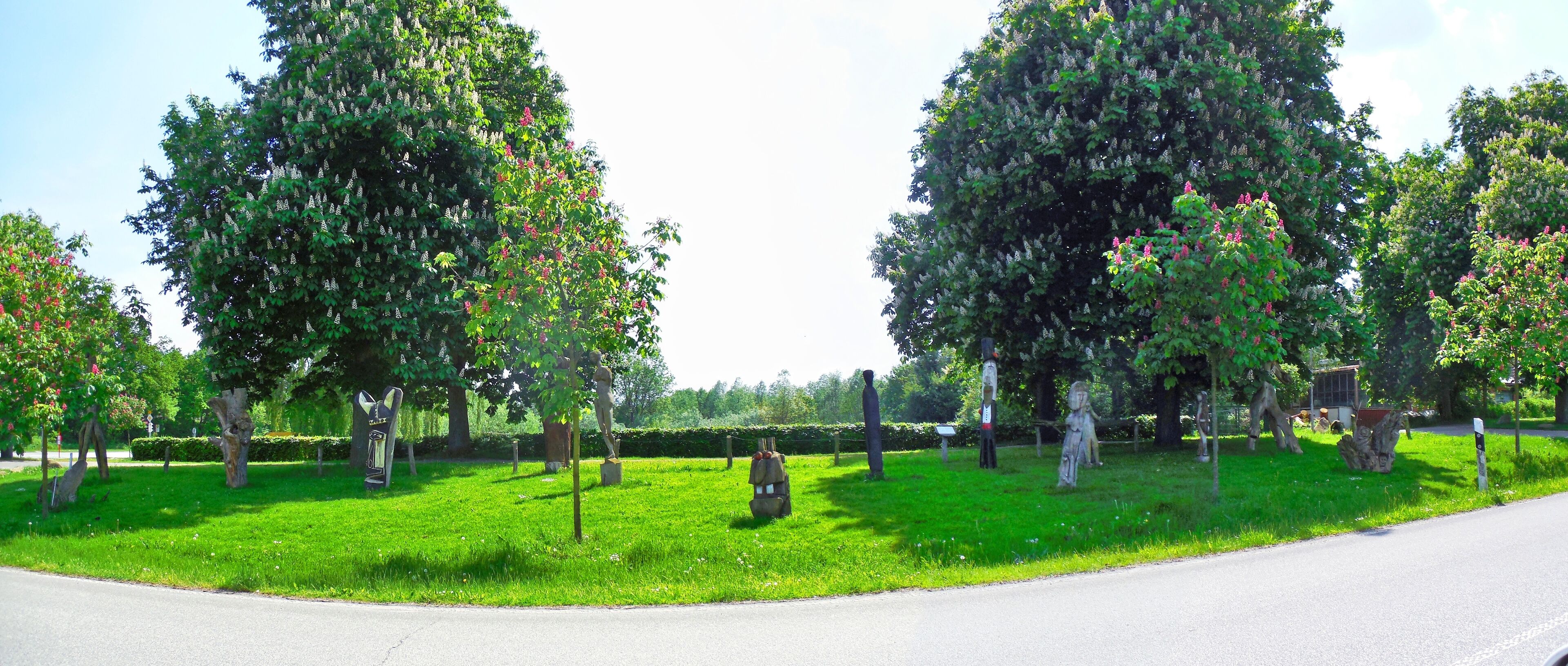 A park with green grass, trees, and statues.