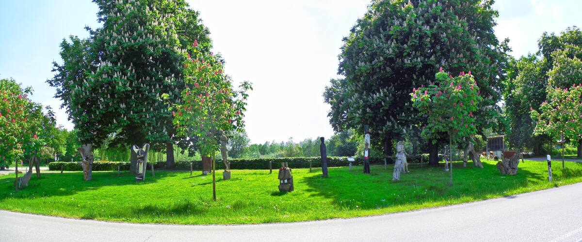 A park with green grass, trees, and statues.