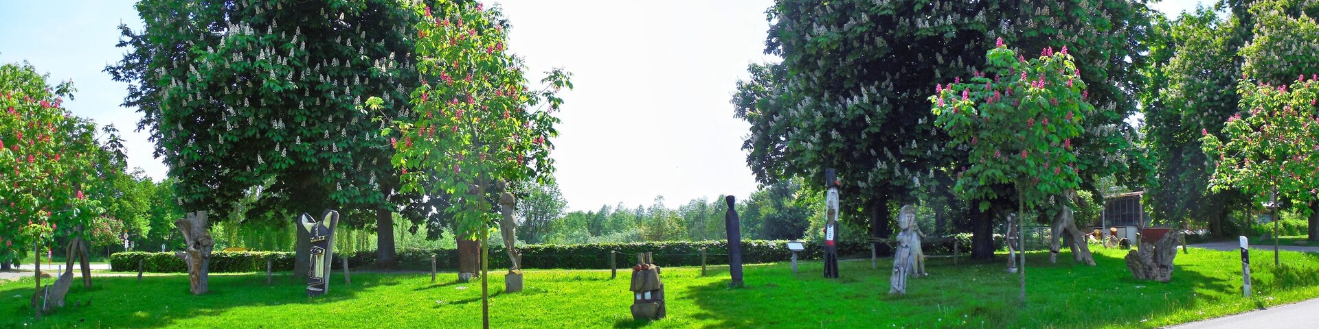 A park with green grass, trees, and statues.