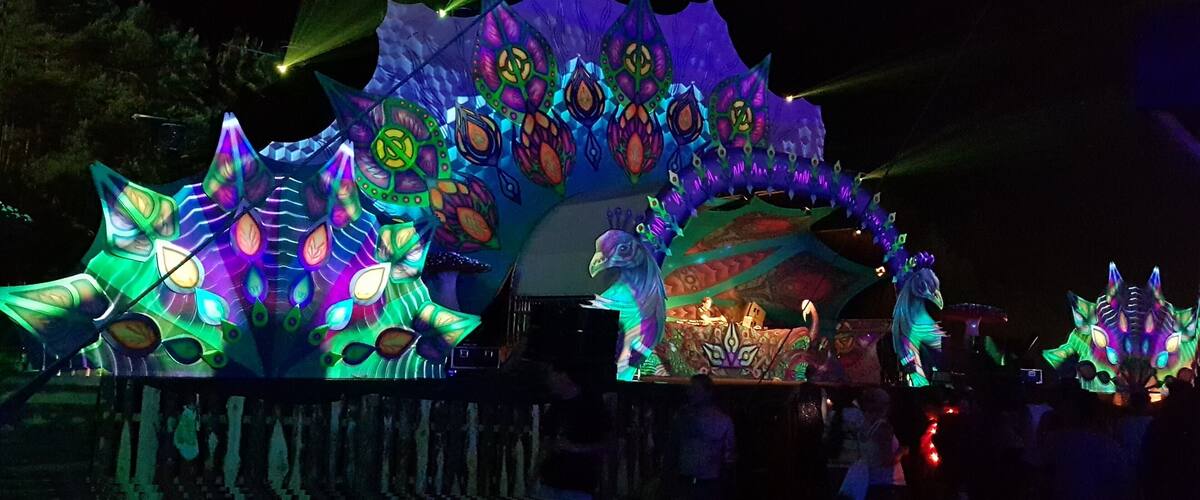A brightly lit, colorful structure with intricate designs and a stage area.