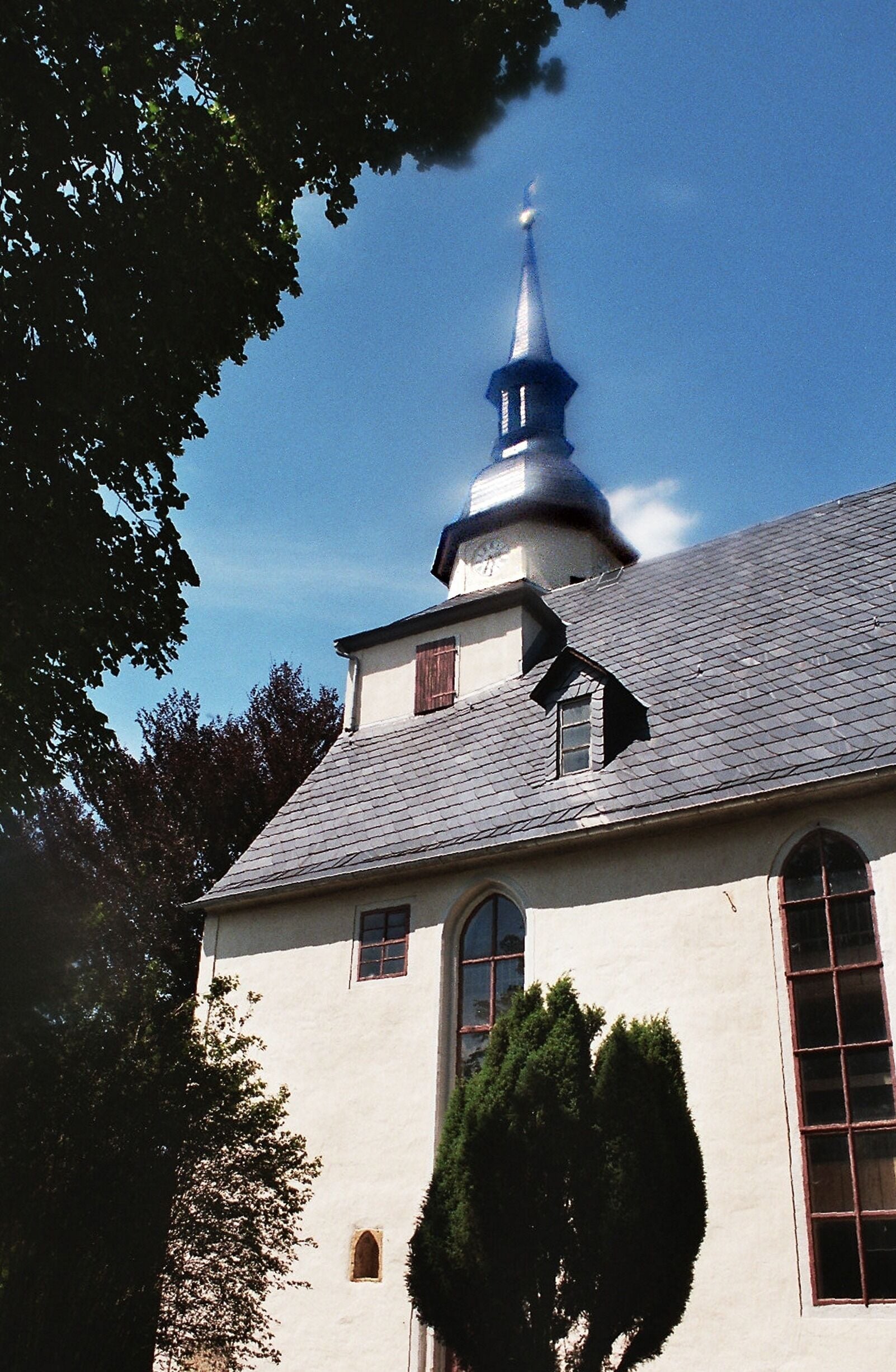 A church with a blue spire and white walls.