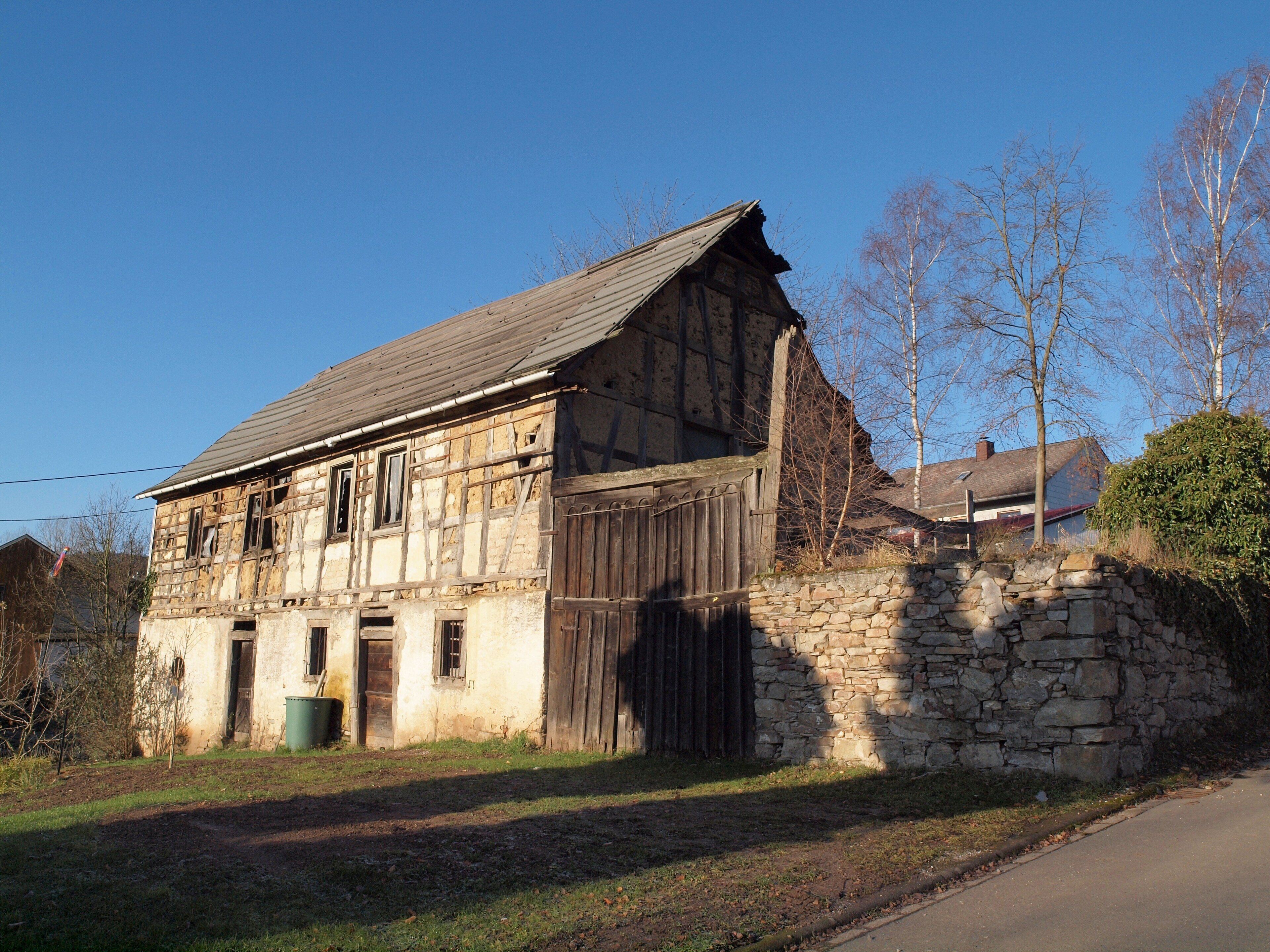A rustic, weathered building with a stone wall foundation and a wooden door.