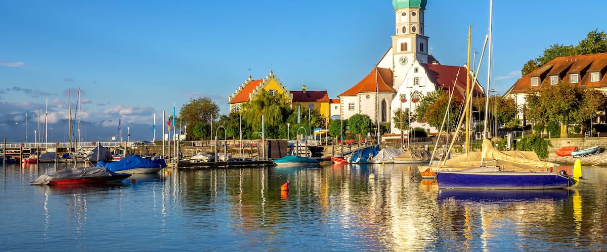 A harbor with boats, a church with a green dome, and colorful buildings.