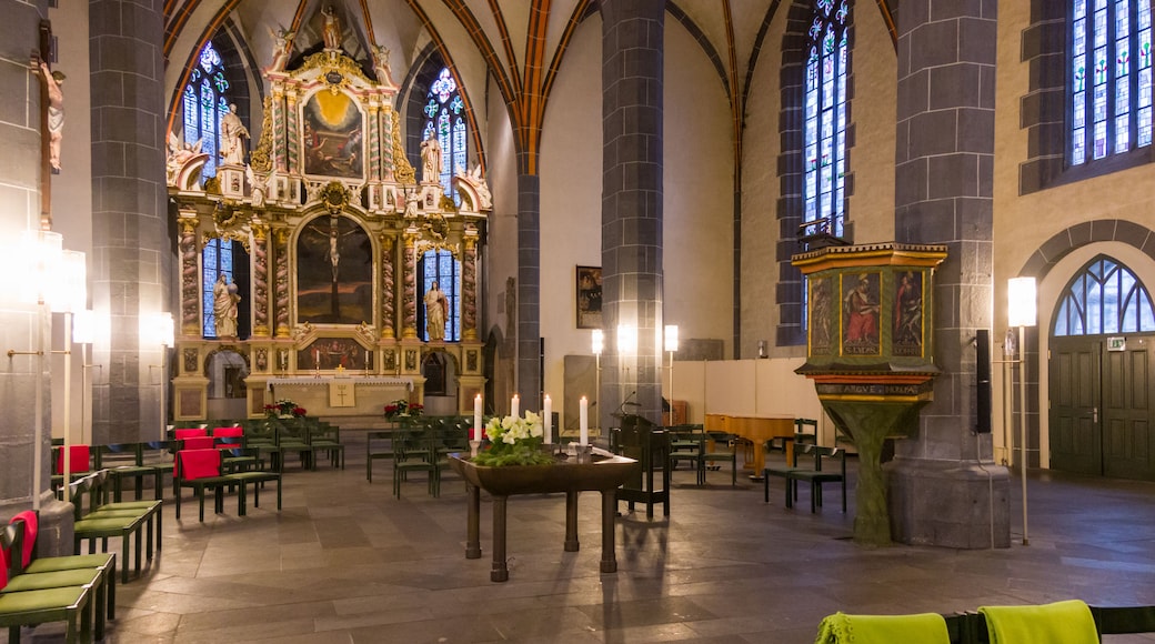 A church interior with Gothic architecture, stained glass windows, and a central altar.