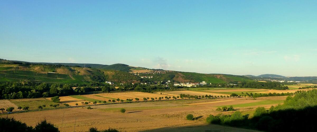 A rural landscape with rolling hills, fields, and scattered houses.