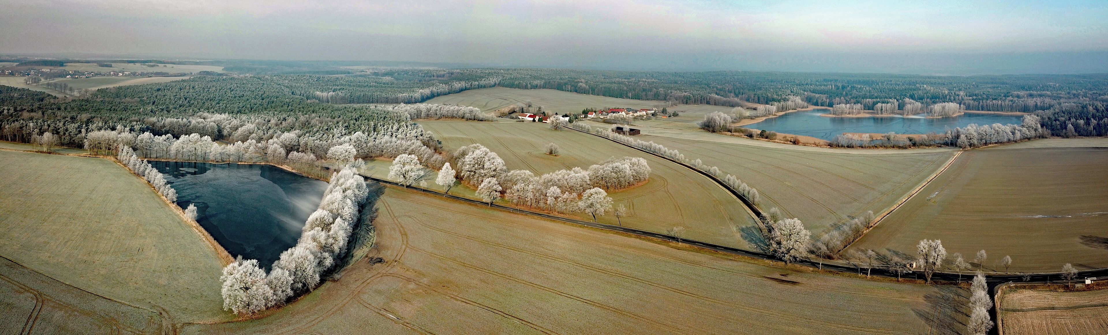 An aerial view of a rural landscape with fields, a river, and a small town.