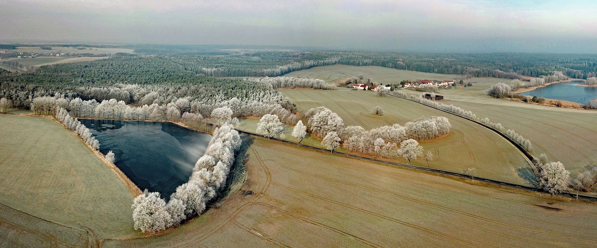 An aerial view of a rural landscape with fields, a river, and a small town.