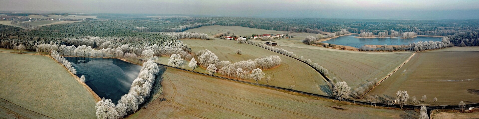 An aerial view of a rural landscape with fields, a river, and a small town.