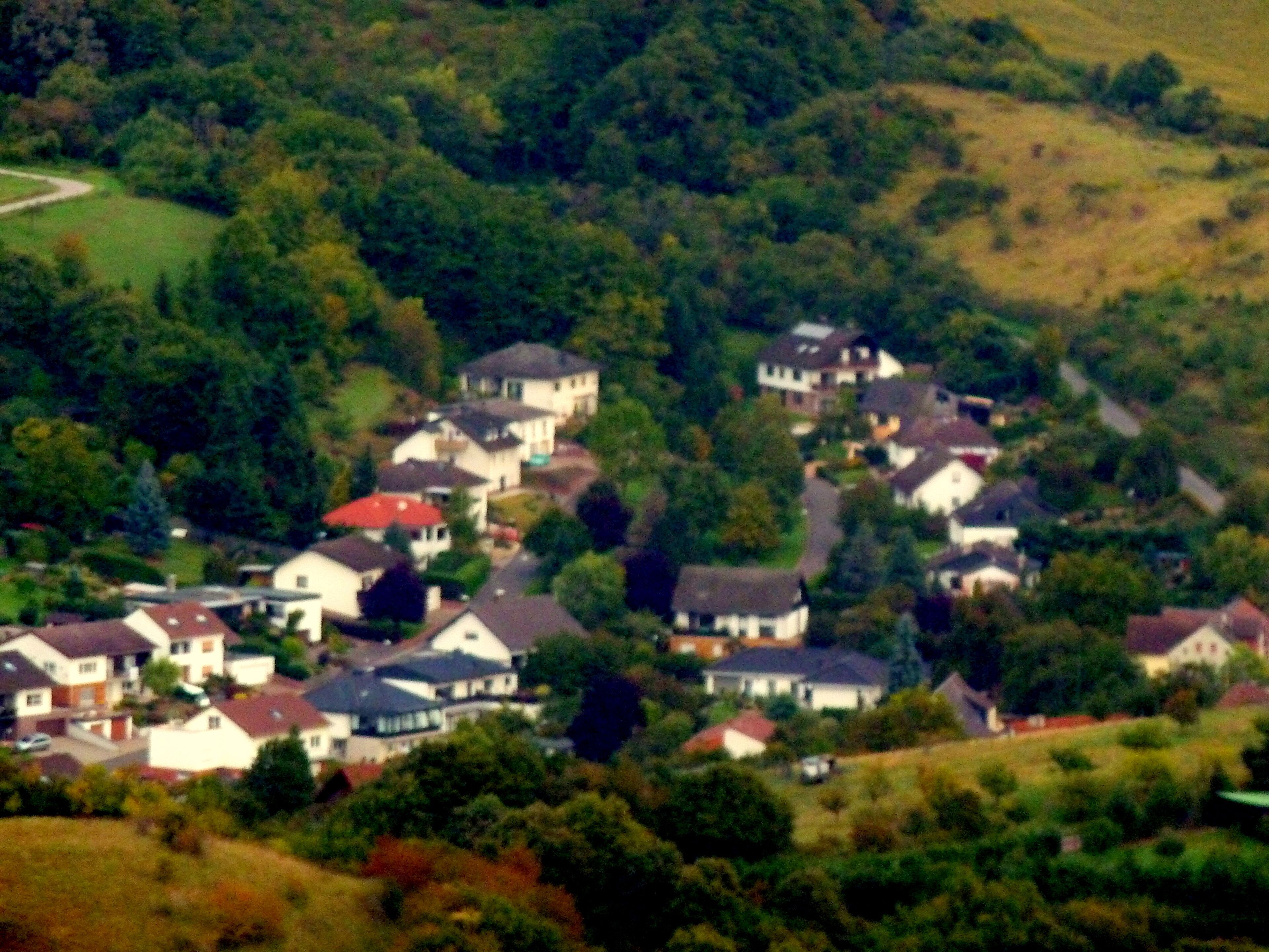 A residential area with houses surrounded by greenery and hills.