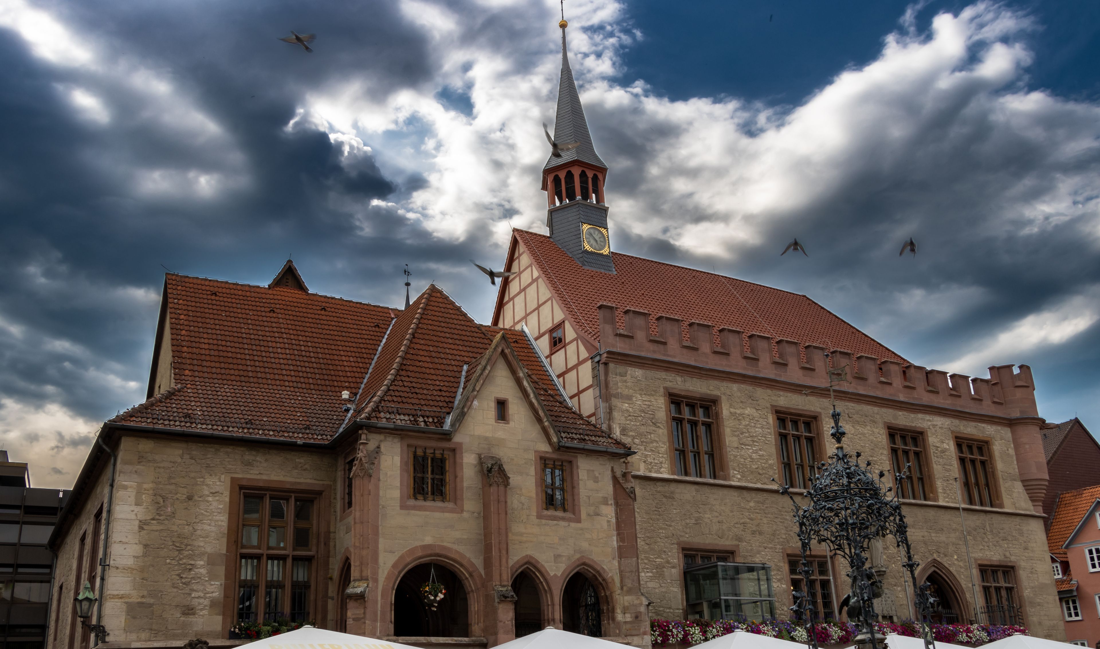 A historic building with a clock tower, red-tiled roof, and arched windows.