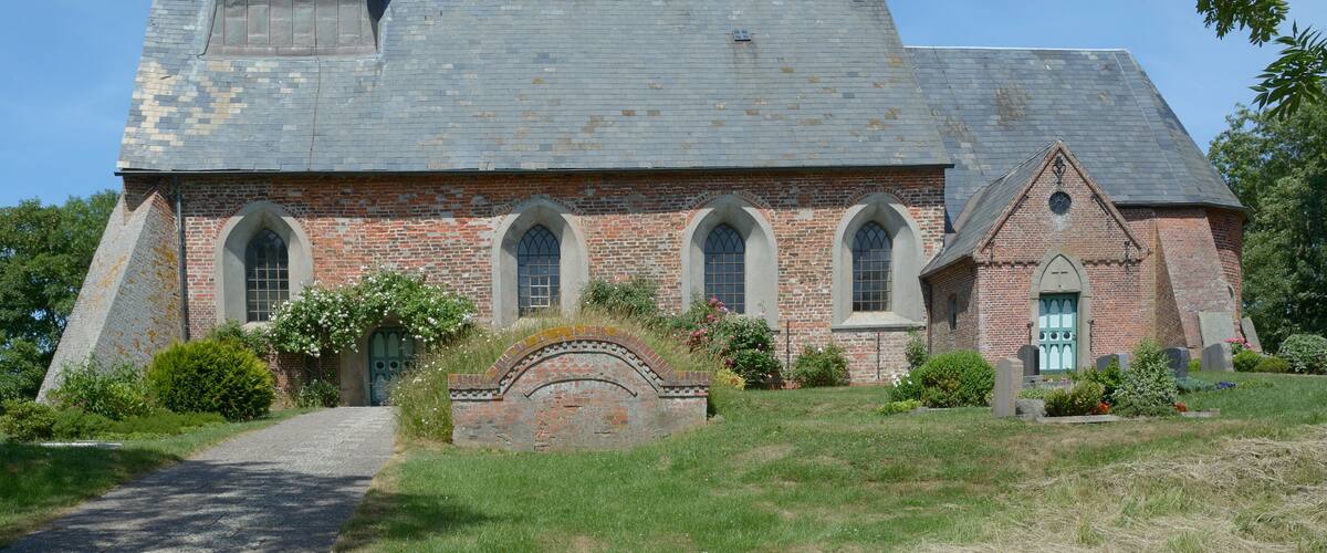A church with a steeple, brick walls, and arched windows.