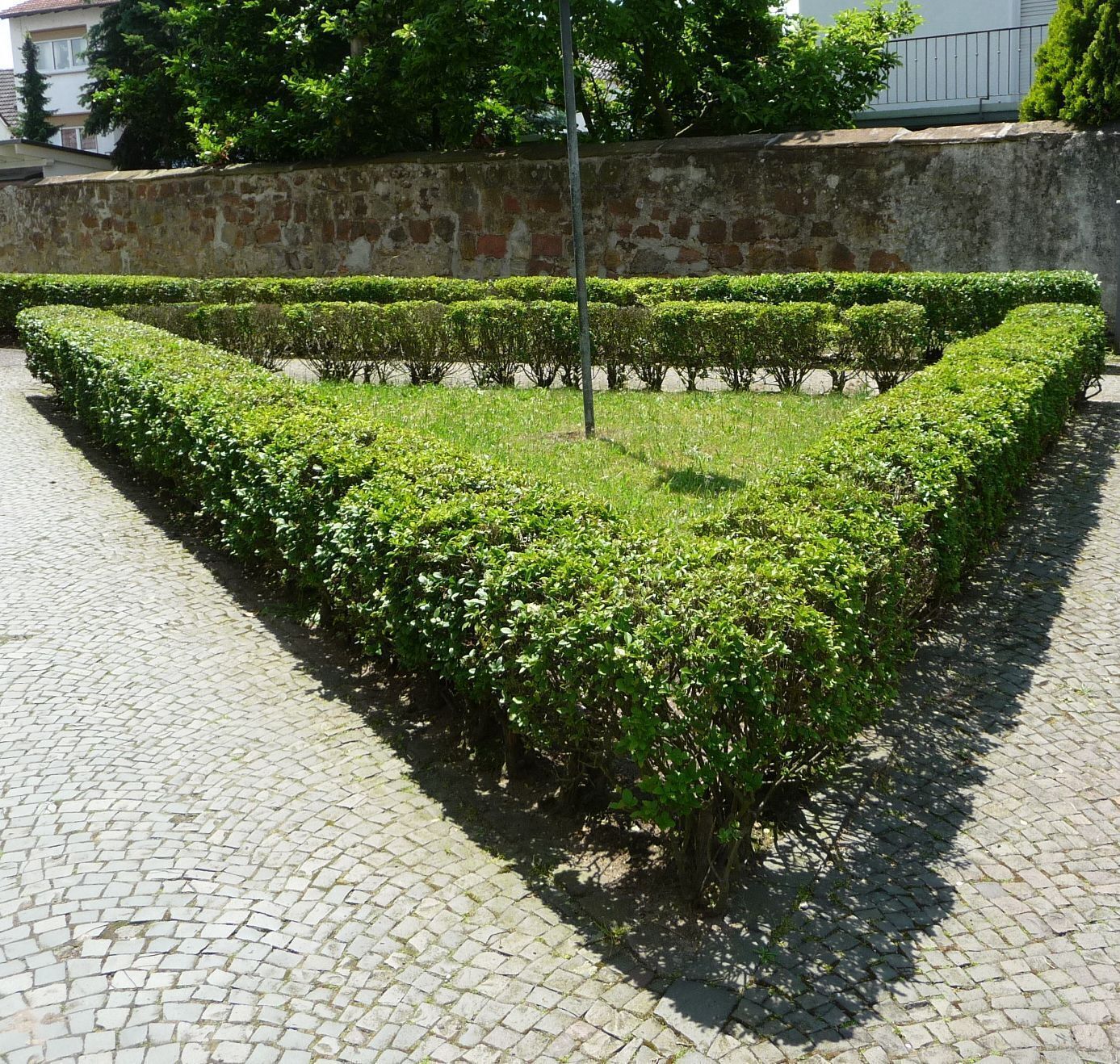 A landscaped garden with neatly trimmed hedges and a cobblestone path.