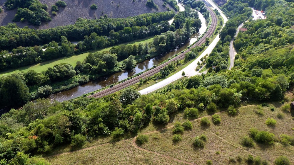 A river winding through a valley with a railway track alongside it.