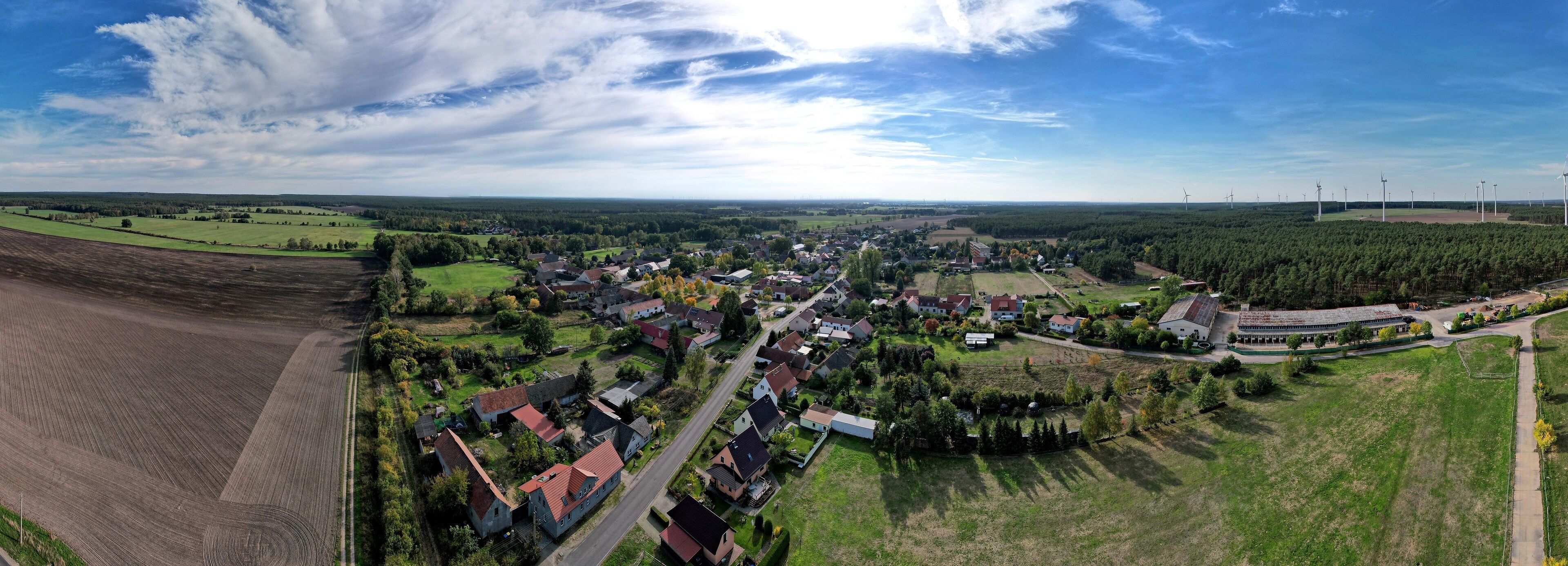 An aerial view of a town with wind turbines, farmland, and residential areas.