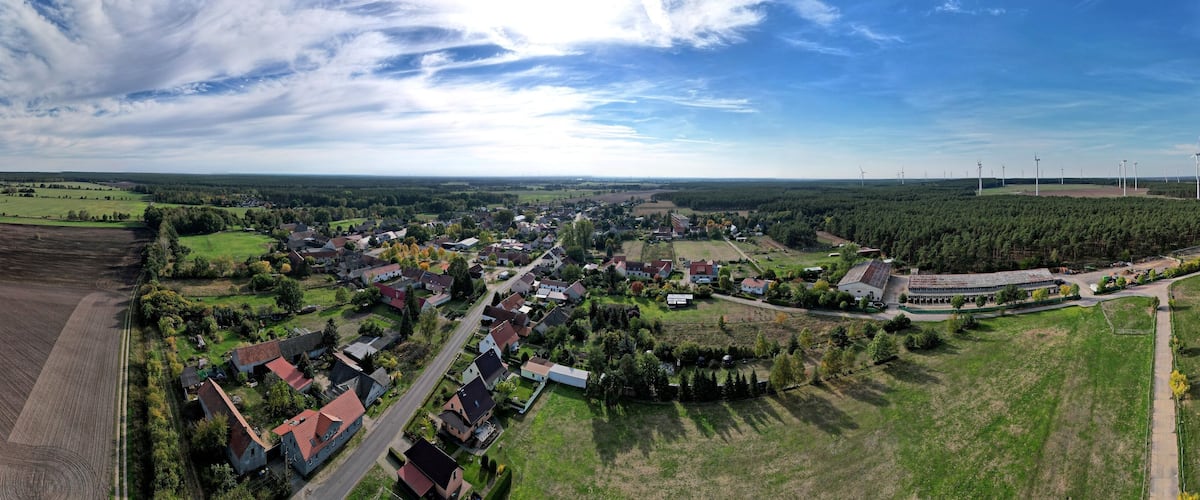 An aerial view of a town with wind turbines, farmland, and residential areas.