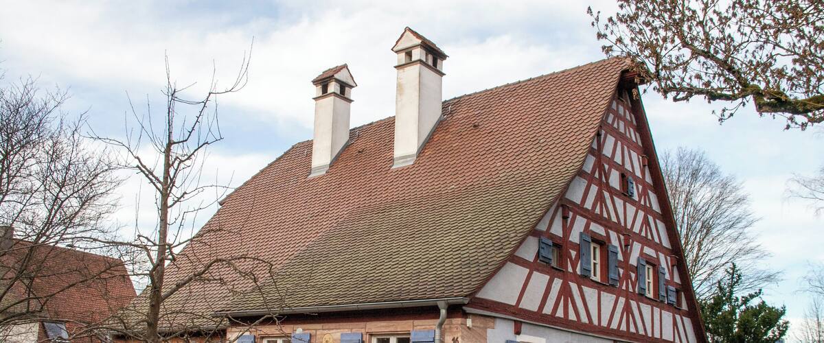 A traditional half-timbered house with a sloped roof and chimneys.