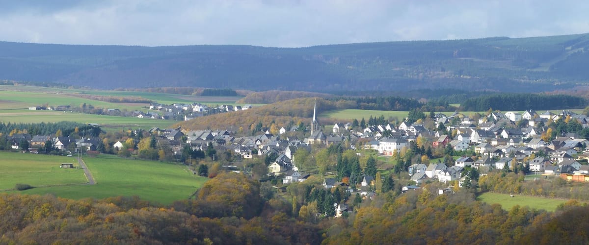 A town nestled in a valley with rolling hills in the background.