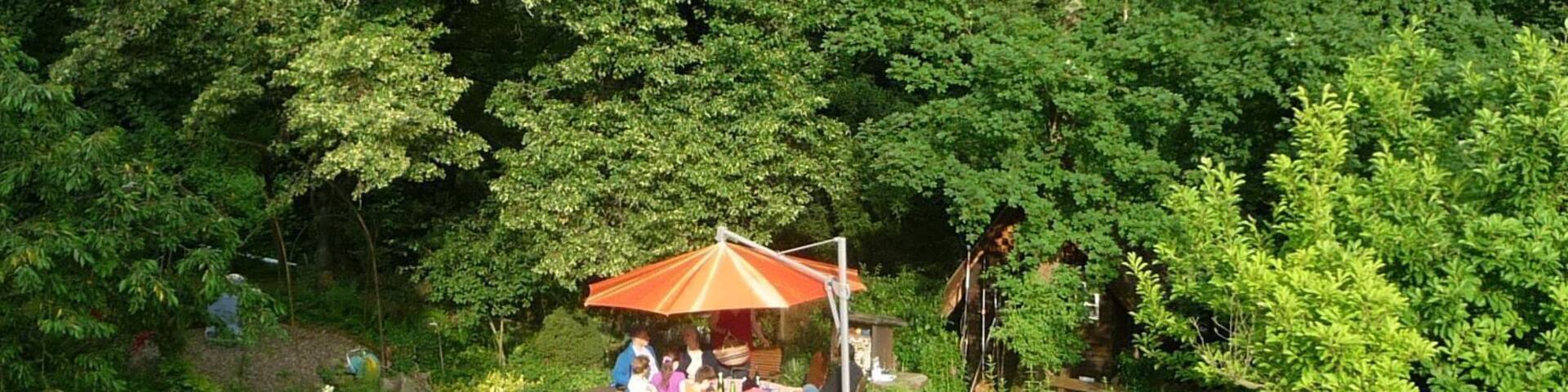A garden with a gazebo, people sitting, and lush greenery.
