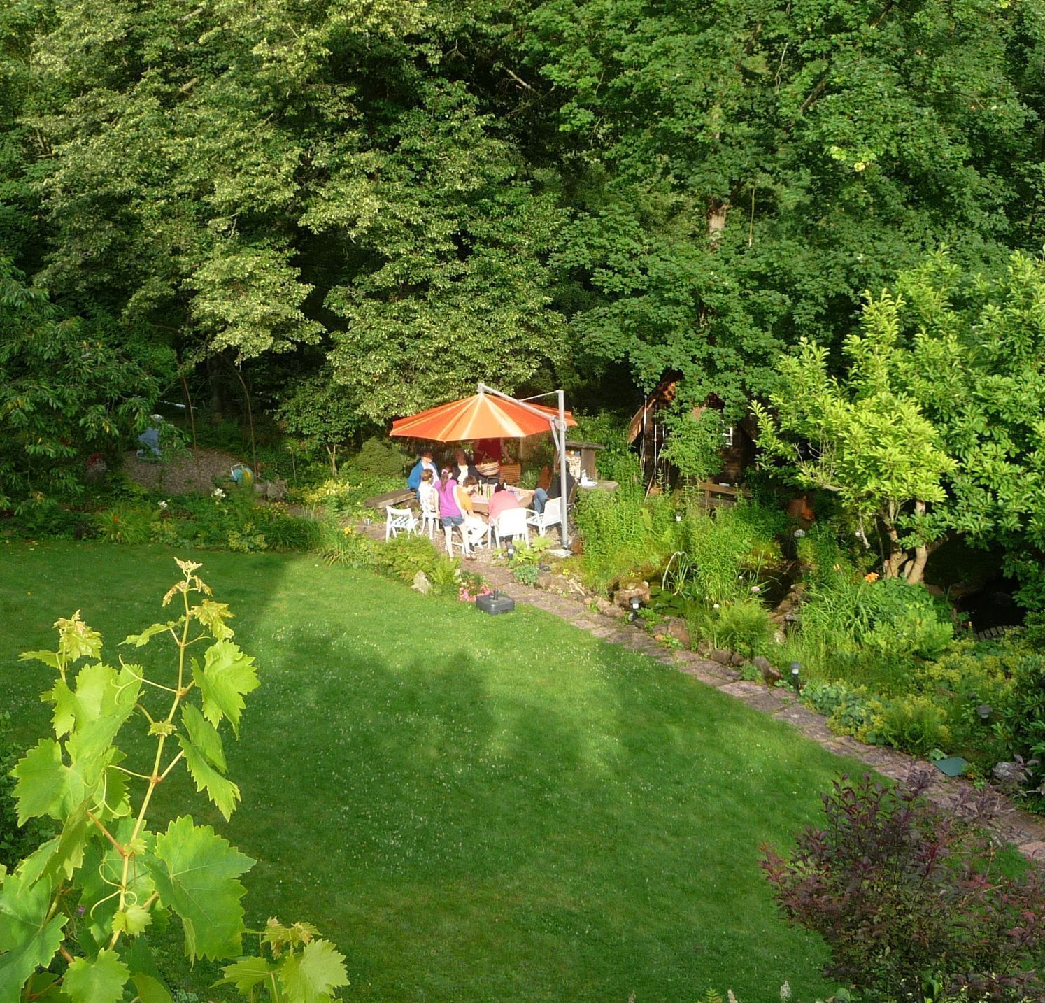 A garden with a gazebo, people sitting, and lush greenery.